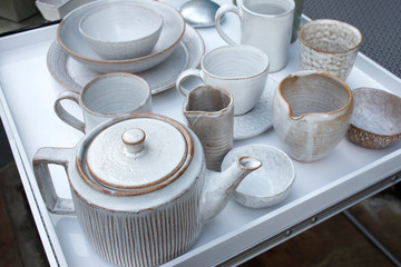 wide variety of plates bowls and mugs lined up for sale at the market.