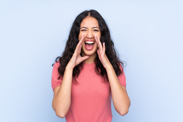 Mixed race woman wearing a sweater over isolated blue background shouting with mouth wide open