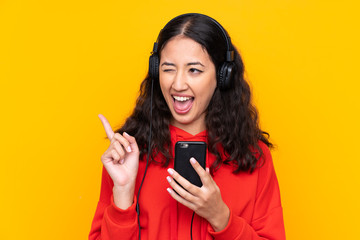 Mixed race woman wearing a red sweatshirt listening music with a mobile and singing