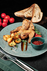 fried quail with a side dish of potatoes, tomatoes and cranberry sauce