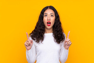 Mixed race woman over isolated yellow background pointing with the index finger a great idea