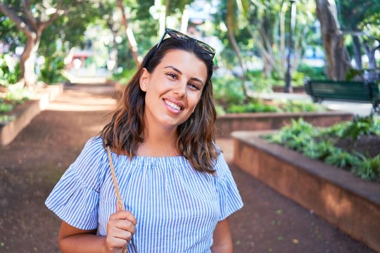 Young beatiful woman smiling happy and cheerful at green park on a sunny day of summer
