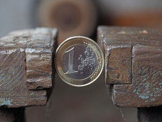 A Euro coin held in a metal grip. Concept of financial problems.