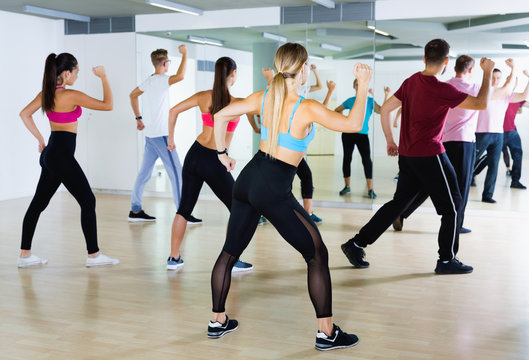 Men women performing modern dance in fitness studio