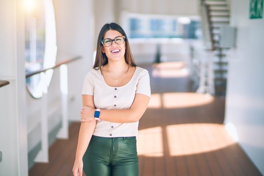 Young beautiful woman on vacation smiling happy and confident. Standing on a deck of ship with smile on face doing a cruise