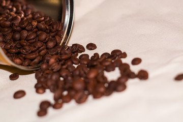 Beans of strong coffee are spread out of the tin can. Morning drink. Background.