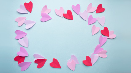 Valentines day background. Multicolored pastel red pink purple lilac hearts on a blue background. Copy space.