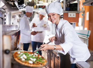 Woman chef getting pizza out of oven
