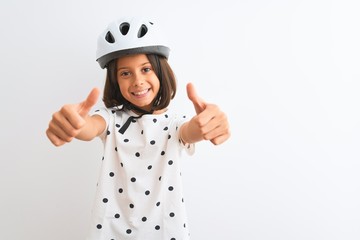 Beautiful child girl wearing security bike helmet standing over isolated white background approving doing positive gesture with hand, thumbs up smiling and happy for success. Winner gesture.