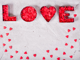 Inscription love made of red hearts on concrete background