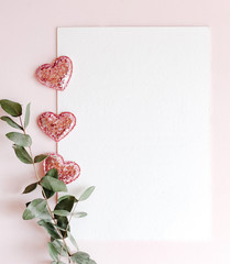 Background with copy space blank on pink background with pink glittered hearts, eucalyptus branch. White paper top view, flat lay, minimal style. Moke up card.