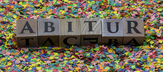 Abitur gedruckt auf Holzwürfel und isoliert auf Konfetti Hintergrund