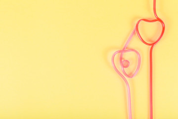 Heart shaped cocktail tubes on a yellow  background.
