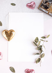 Background with copy space blank on white table with glitter heart, eucalyptus branch, flowers and leafs. White paper top view, flat lay, minimal style. Moke up card.