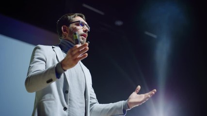 Portrait of Inspirational Innovative Speaker, Talking about Happiness, Self, Success, Empowerment, Efficiency and How to Be More Productive Self. Large Conference Hall with Cinematographic Light