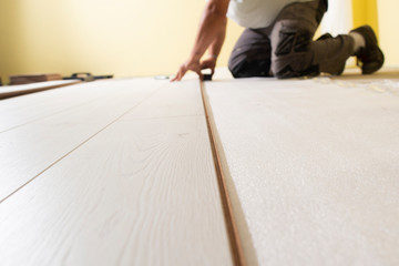 Man installing laminate floor in new house