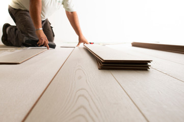 Man installing laminate floor in new house