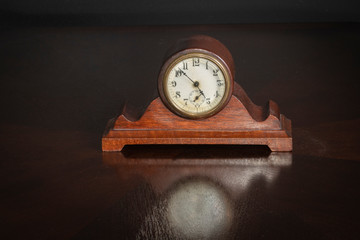Small Wood Antique Clock on an oak table with reflection 7 to 5