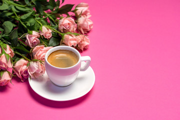 Pink roses and cup of coffee on bright pink background. Valentine's day concept, top view with copy space, women's day.