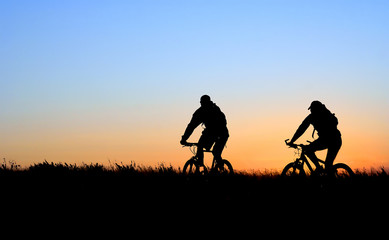 Mountain bikers in silhouette at sunset