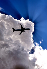 Airliner silhouetted against a bright cloud