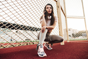 Beautiful fitness woman in sportswear posing near grid.