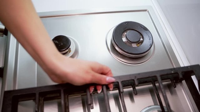 Woman cleaning gas stove. Hand of woman cleaning gas cooker with sponge in the kitchen