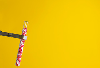 test-tube, beaker fill candy hearts on yellow background