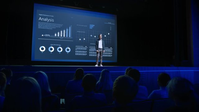 Business Forum Economics Conference Stage: Professional Speaker Concludes His Report with a Speech and Showing Infographics, Statistics on the Big Screen. Audience Applauds