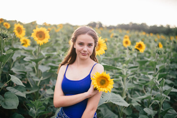 Beautiful girl on the field with sunflowers in short shorts and a vest