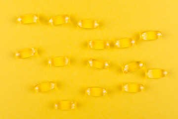 golden omega capsules on yellow background closeup