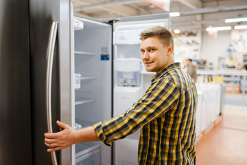 Fototapeta na wymiar Man choosing refrigerator in electronics store