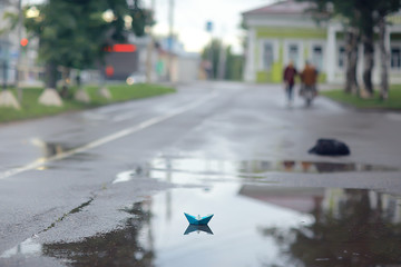 paper boat in a puddle of rain / autumn weather concept childhood