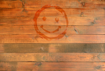 Smile emoticon on the background of the wood surface. Drawn smiley smile symbol. Joyful sign.