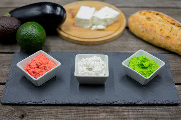 Fototapeta na wymiar Various dips in bright colors from avocado, aubergine and sheep's cheese decoratively arranged.
