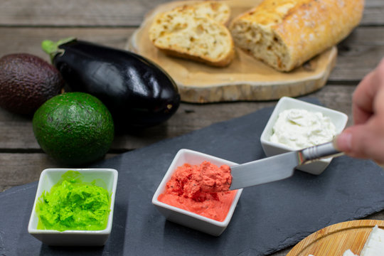 delicious dips in bright colors from avocado, aubergine and sheep's cheese with knife in an aubergine dip.