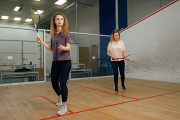 Two players with squash racket playing on court