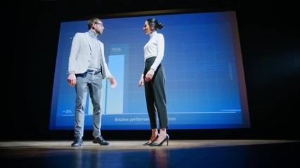 On Stage, Successful Female CEO and Male COO Speakers Present Company's New Product, Show Infographics, Statistics on Big Screen, Talk About Growth. Live Event, Tech Startup, Business Conference