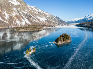 Aerial image of the Chaviolas islets on the frozen lake of Silsersee in St. Moritz, Switzerland