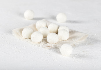 Fototapeta na wymiar Balls of cottage cheese with coconut shavings on a white linen napkin on a light background