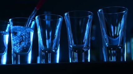 alcohol pours into a glasses in a bar background