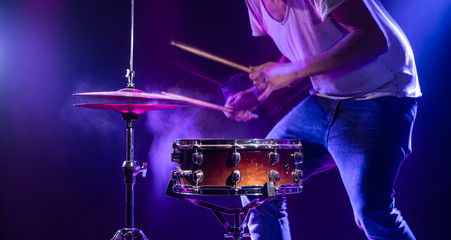 A drummer plays drums on a blue background. Beautiful special effects of light and smoke. The...