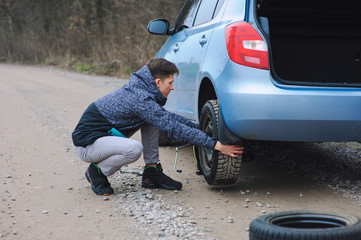 Man is changing tire with wheel on the car