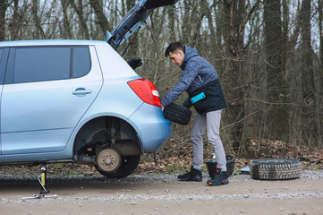 Man is changing tire with wheel on the car