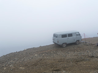 Car on the brink of an abyss in the fog of the clouds. Caucasus mountains