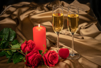 Valentine's day card, two glasses of champagne on a gold background red roses and a red heart, a lighted candle