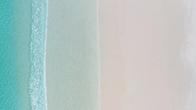 Aerial shot of turquoise water and waves rolling in onto the sand of Australia's whitest beach - Lucky Bay