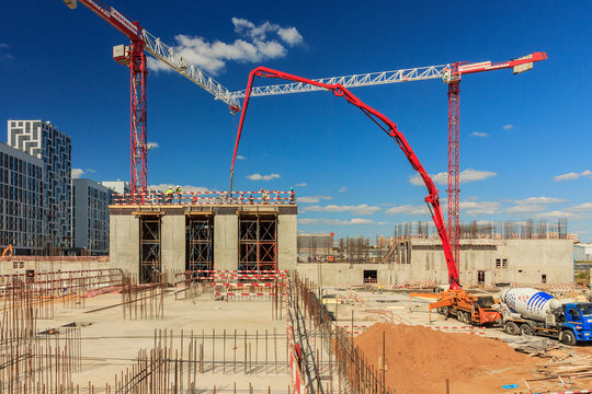 concrete pump building under construction. Concrete pump on high rise building under construction site with crane. Cement mixer truck with pump is preparing to put concrete on foundation. 