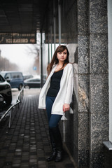 Girl in winter in a cardigan on a street in the city