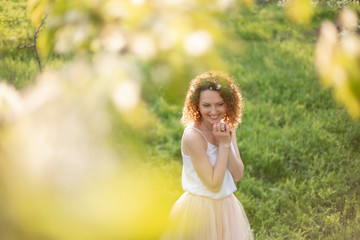 Young attractive girl walks in spring green park enjoying flowering nature. Healthy smiling girl spinning on the spring lawn. Allergy without